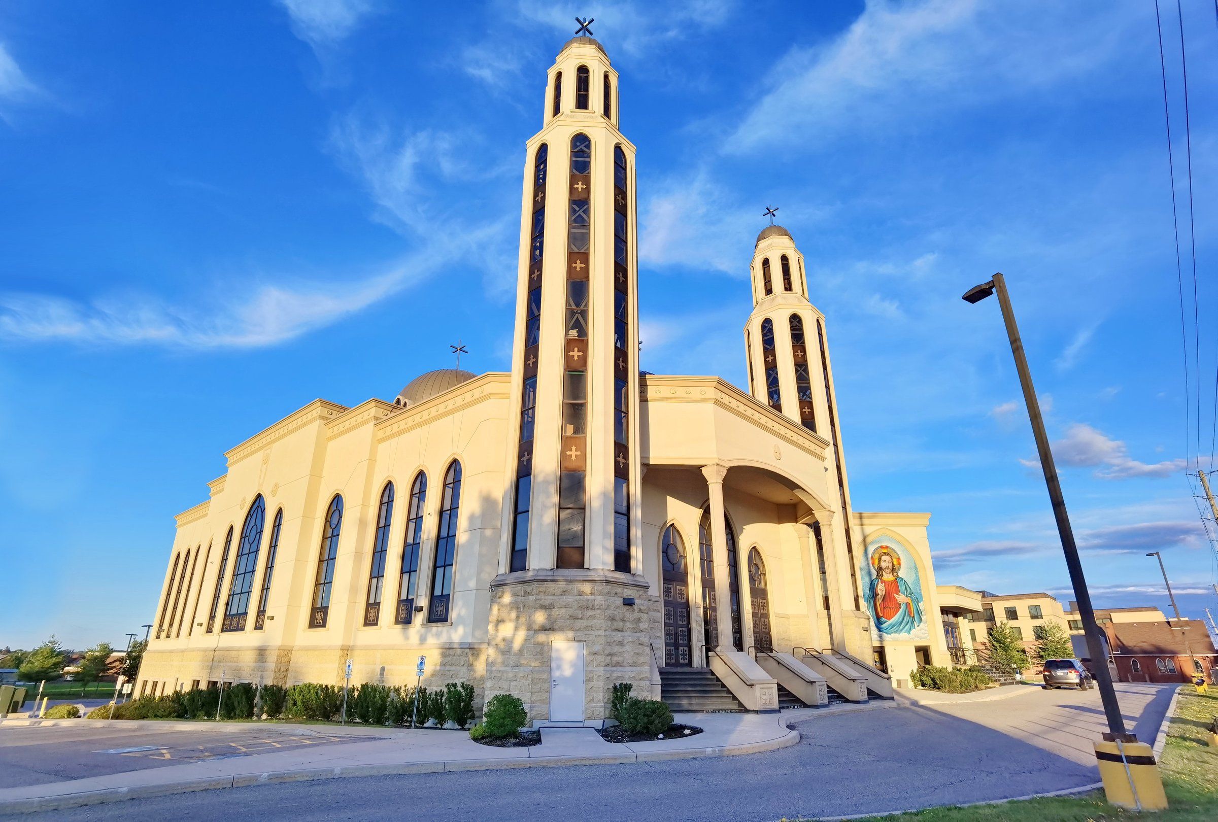 The Coptic Orthodox Church of Archangel Michael and St. Tekla, a cream-coloured church with two tall bell towers and an icon of Christ beside its entrance