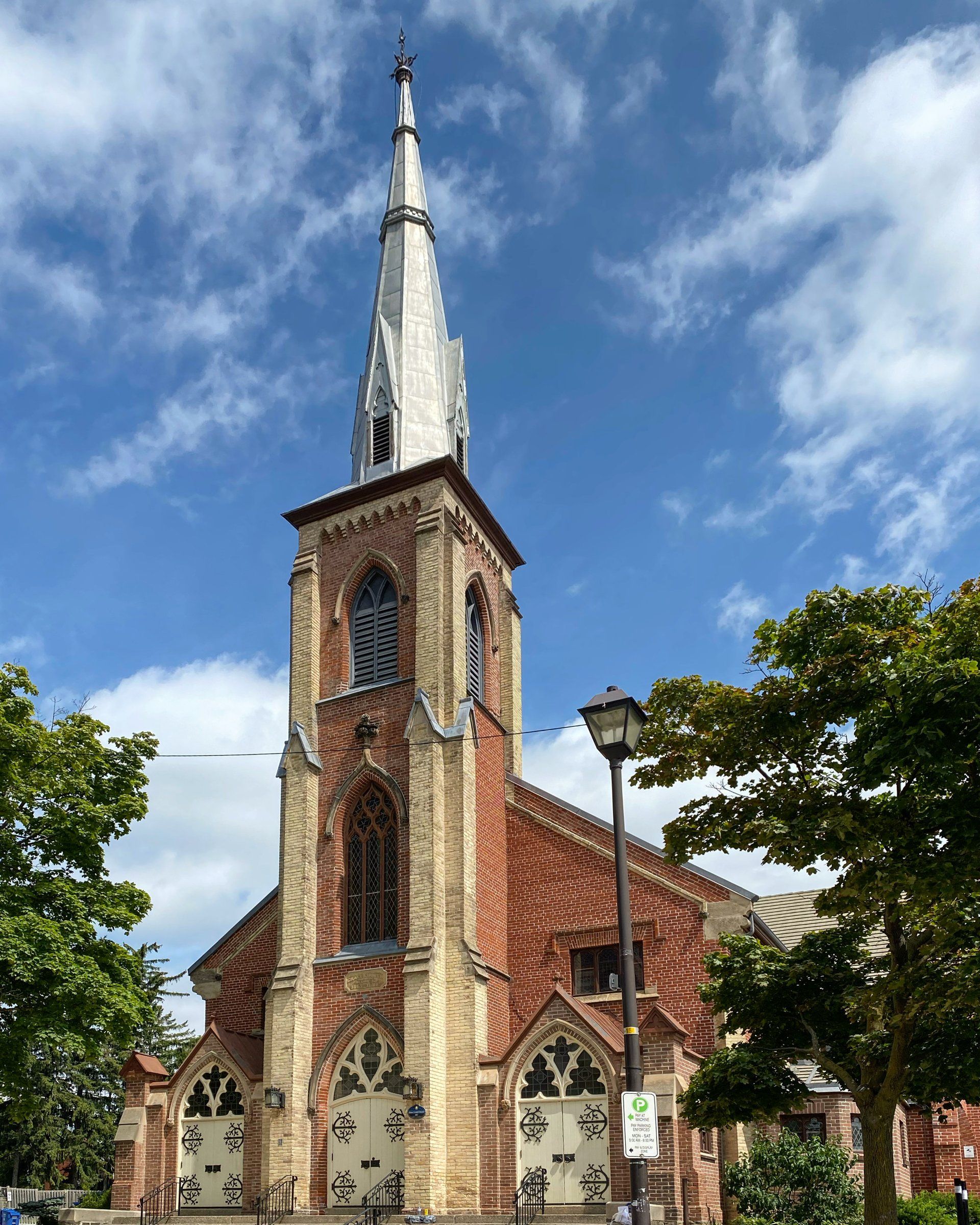 Grace United Church, a red and buff brick church with a tall pointed spire, against a blue sky