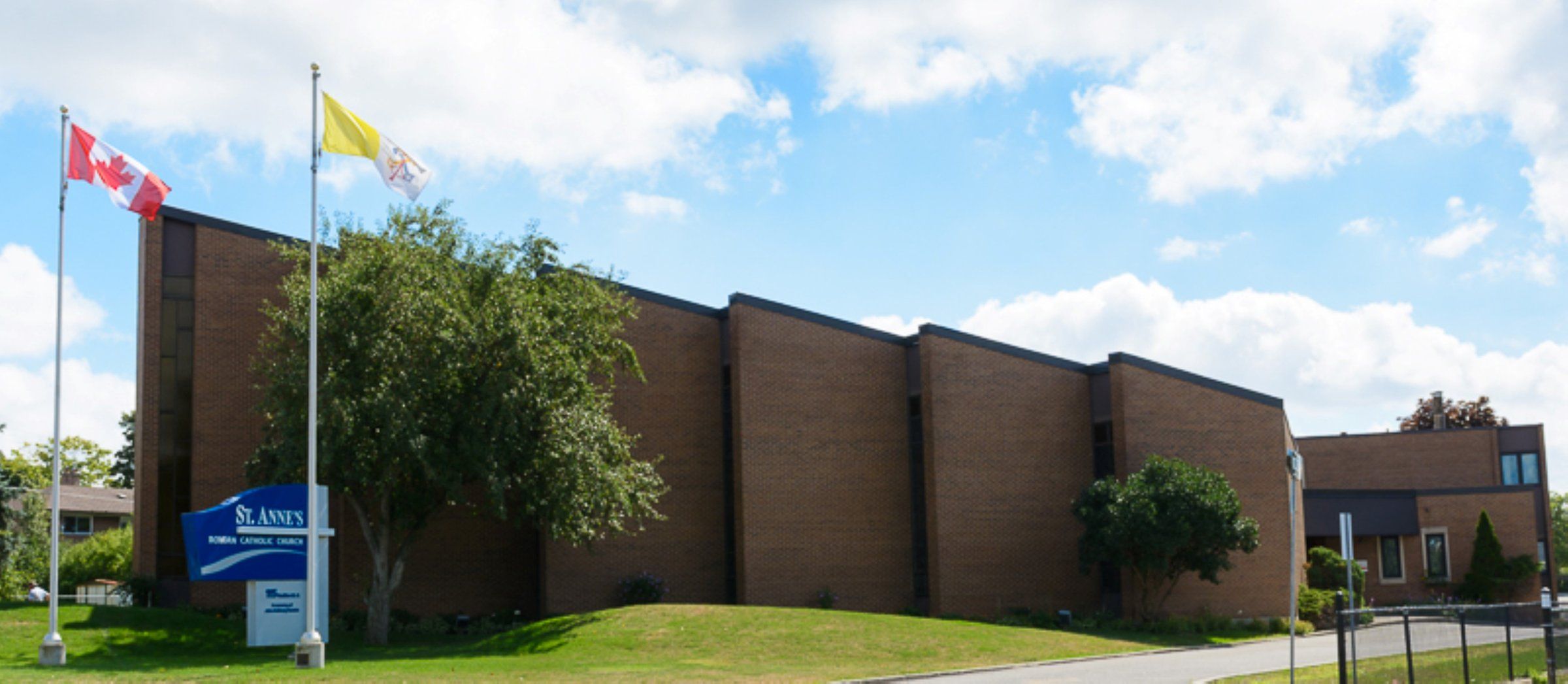 St. Anne's Catholic Church, a long brown-brick building with flags flying beside its sign on the front lawn
