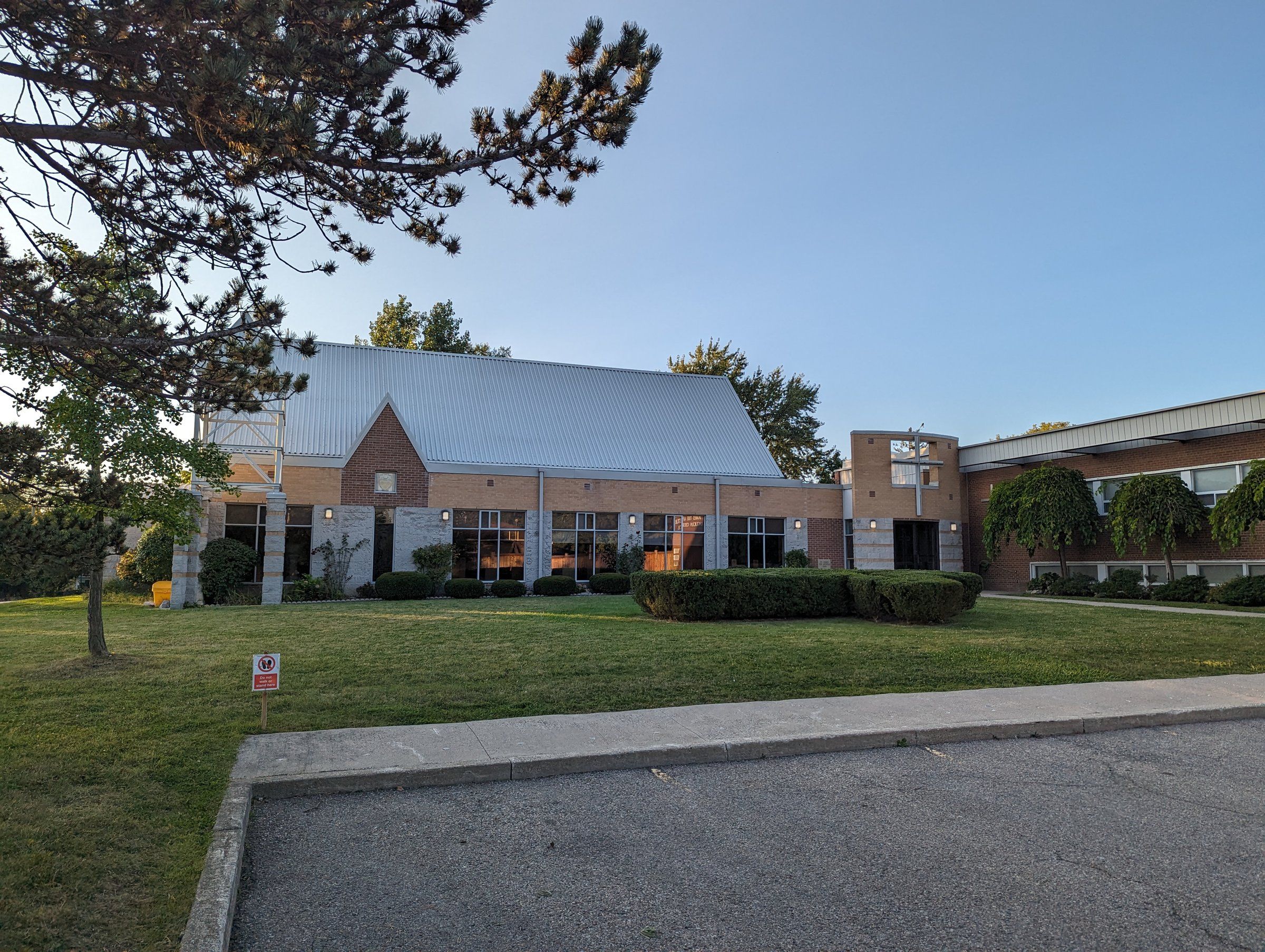 St. James the Apostle Anglican Church, a low brick church with a long grey roof and a gabled front, seen across a lawn
