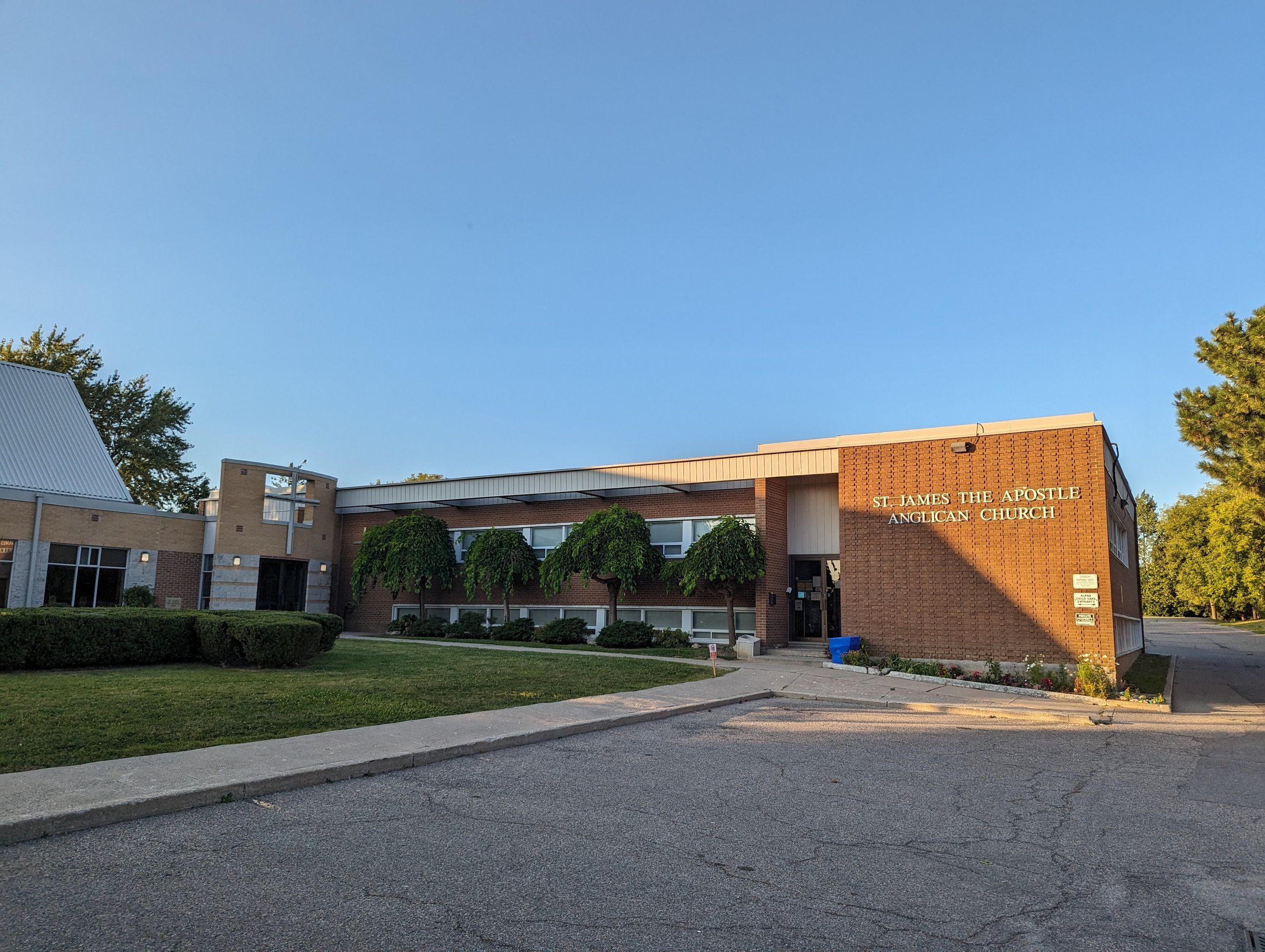 The flat-roofed brick wing of St. James the Apostle, with the church's name lettered on the wall beside the entrance